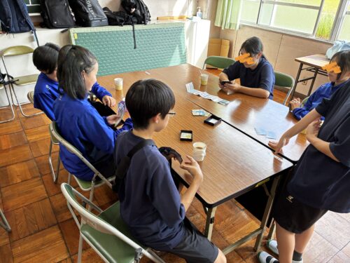 テーブルを囲んでカードゲームを遊ぶ中学生たち